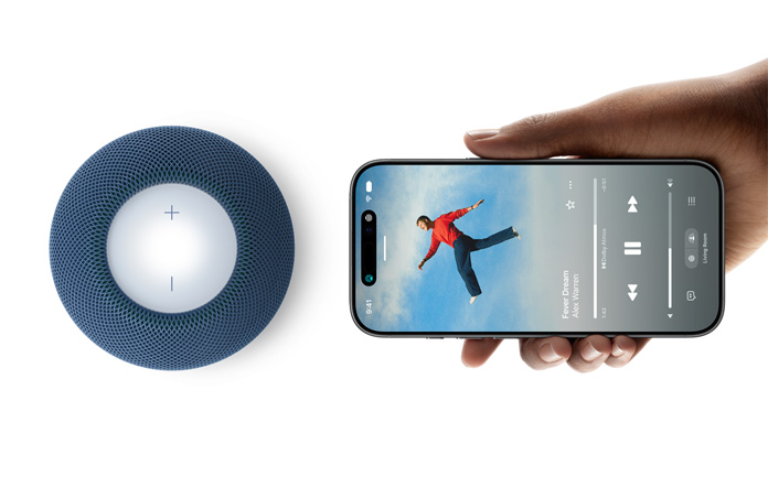 HomePod mini 2 and iPhone: A hand holds iPhone beside blue HomePod mini 2 for handoff feature