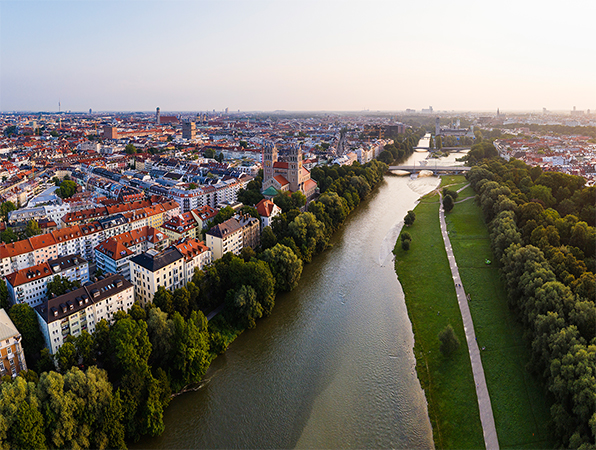 Aerial view of Munich with a river, trees, and a walking path alongside the river.