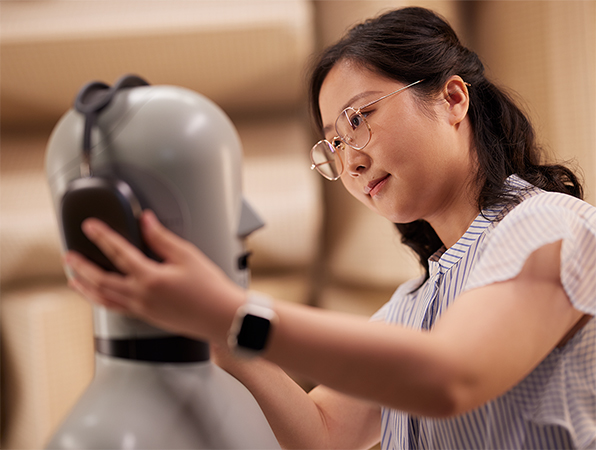 Empleada de Hardware de Apple acomodando unos AirPods Max de Apple en un maniquí de laboratorio.