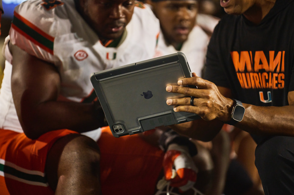 Un entrenador y jugadores de Miami revisan videos en un iPad en la línea lateral durante el partido.
