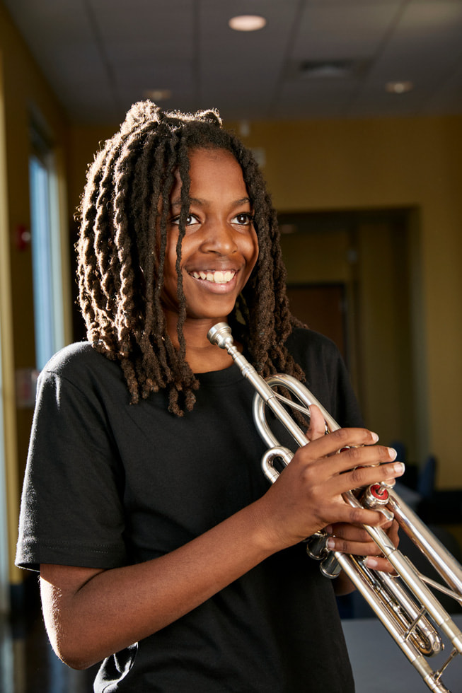 Ellis Marsalis Center participant Donte Allen plays the trumpet outside of the center.
