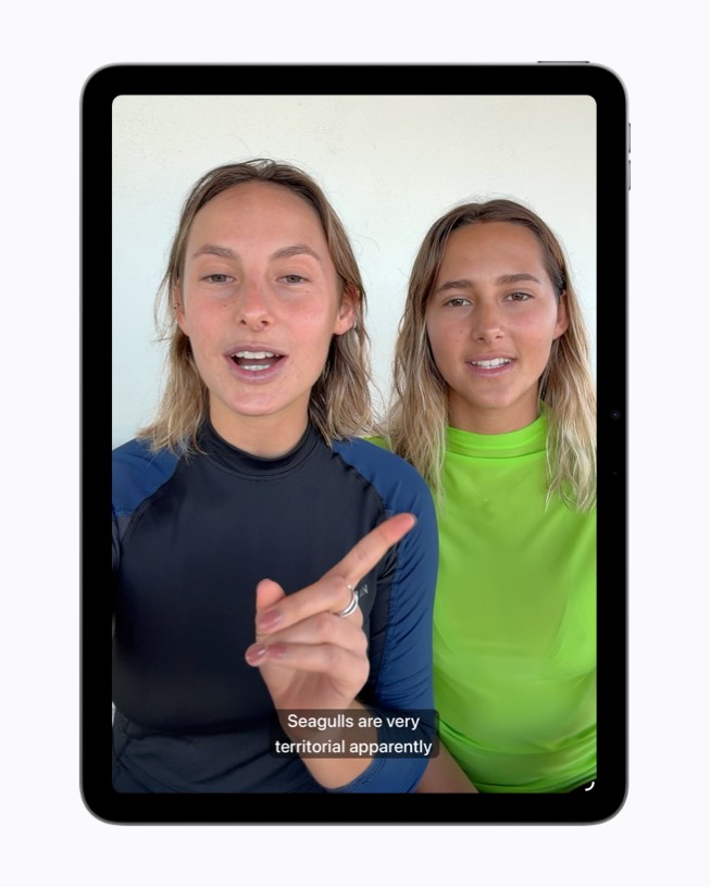 Op een iPad is een videobeeld te zien van twee mensen die aan het praten zijn, met daaronder gegenereerde ondertitels.