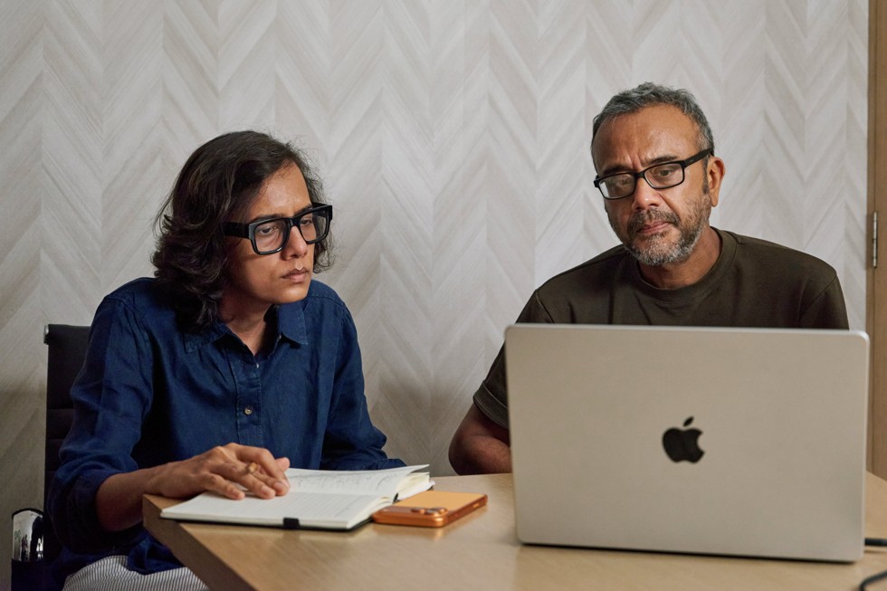 Dhritisree Sarkar zit met een collega aan een tafel met daarop een MacBook Pro en een iPhone 17 Pro Max.