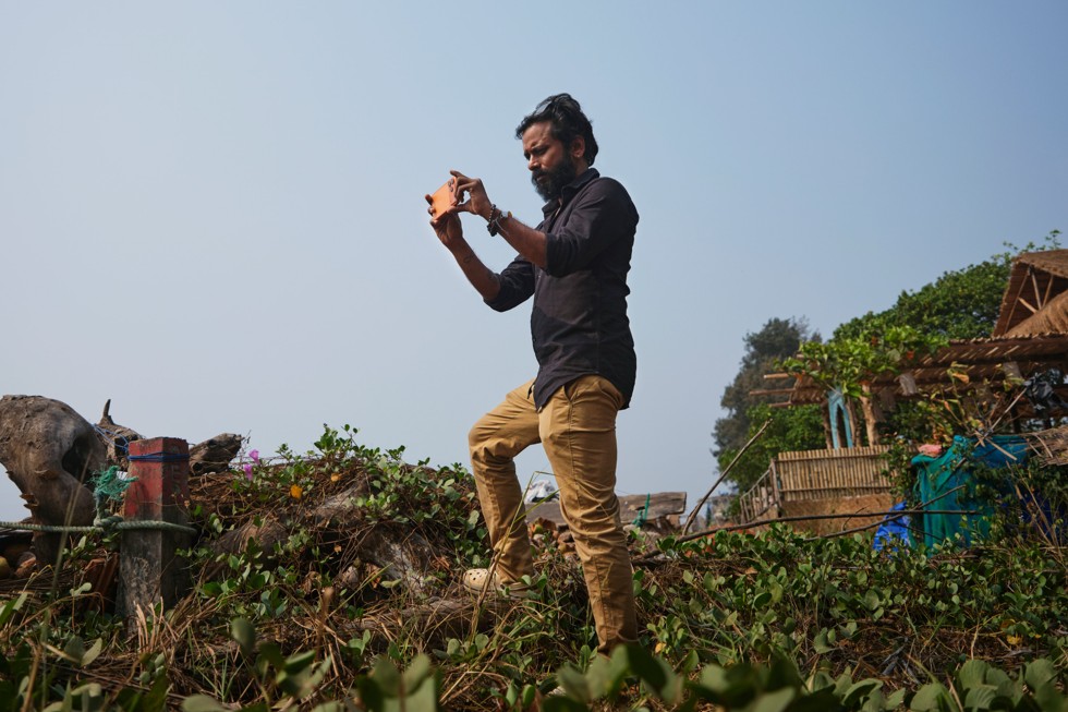 Ritesh Sharma staat op een begroeide heuvel te filmen met iPhone 17 Pro Max.