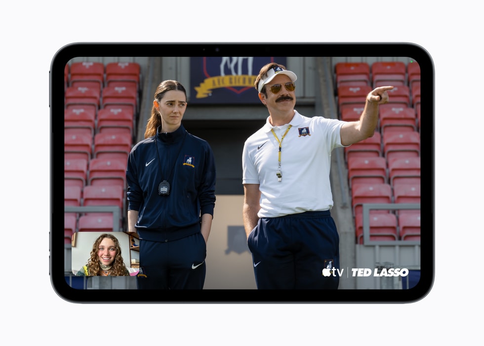 Ein iPad mini zeigt einen Bildschirm aus dem Apple TV Original „Ted Lasso“ sowie einen FaceTime Anruf. 