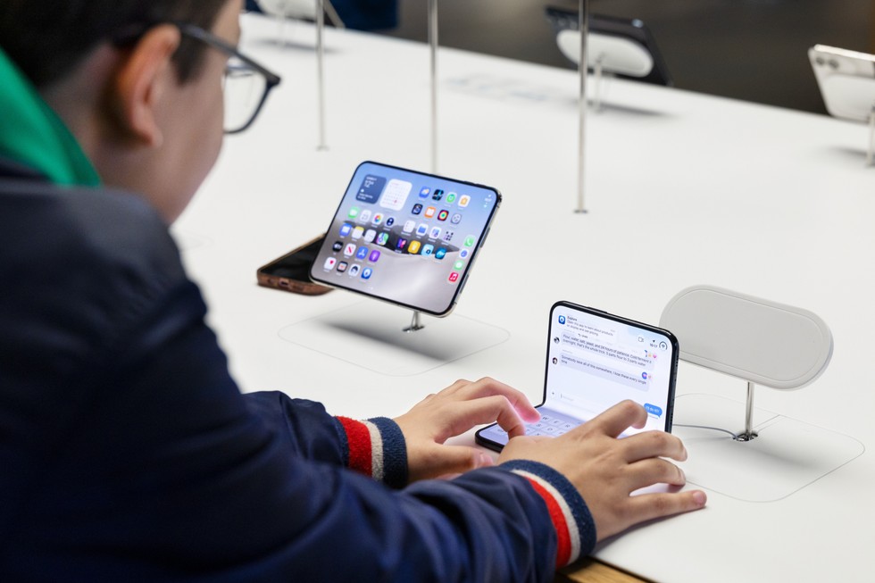 At Apple Covent Garden, a customer types on iPhone Duo at a display table.