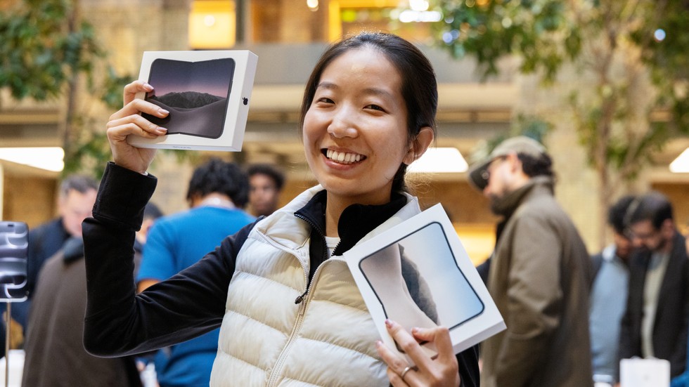 At Apple Covent Garden, a customer holds up two iPhone Duo purchases.
