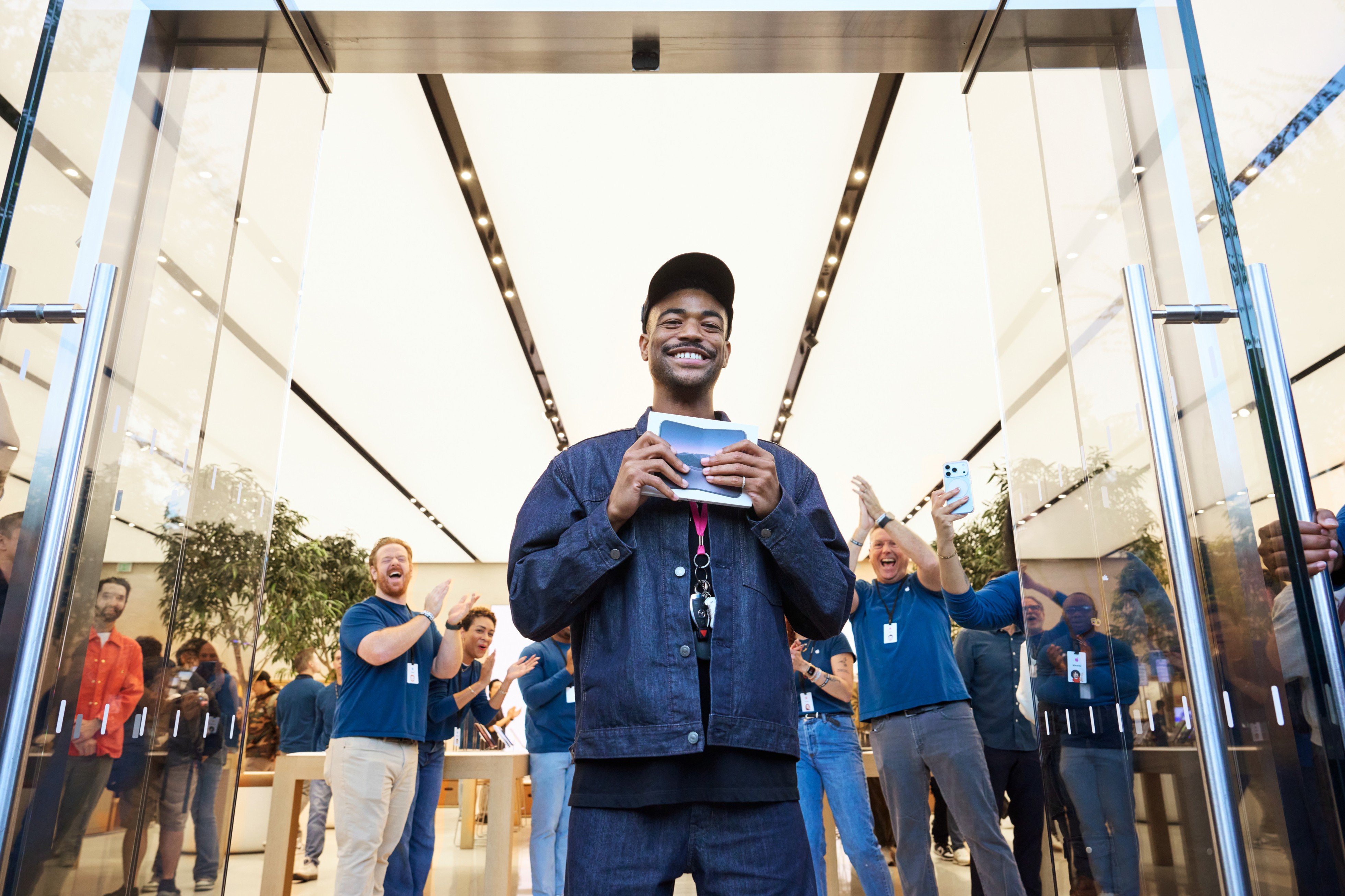 In front of Apple Domain NORTHSIDE, a person holds up iPhone Duo in its packaging, as team members cheer in the background.