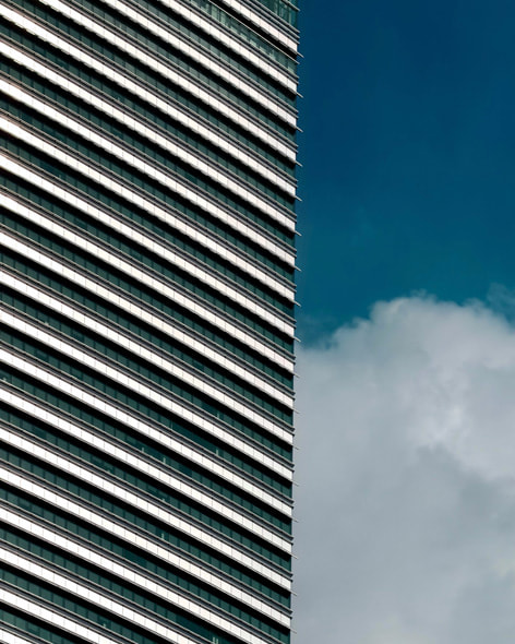 クアラルンプールにある超高層ツインタワーの一部である円形の建物のクローズアップ写真。その背後に、さらに高いタワーがそびえ立っています。
