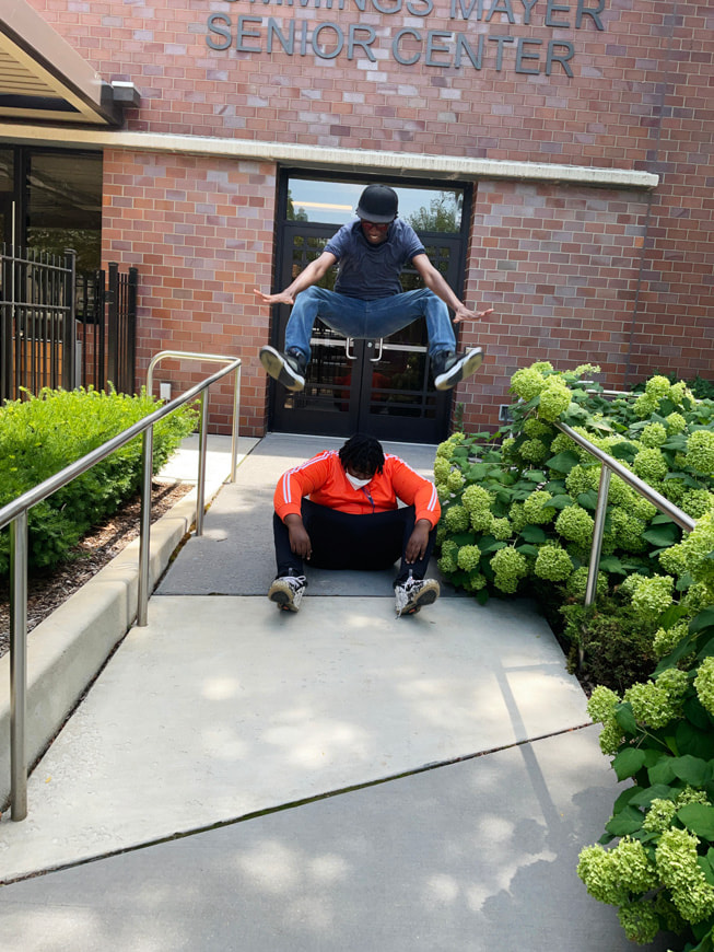 Gisselle Ayala’s action photo shows Glen-David Hardy-Covington and John Johnson in front of a senior center.