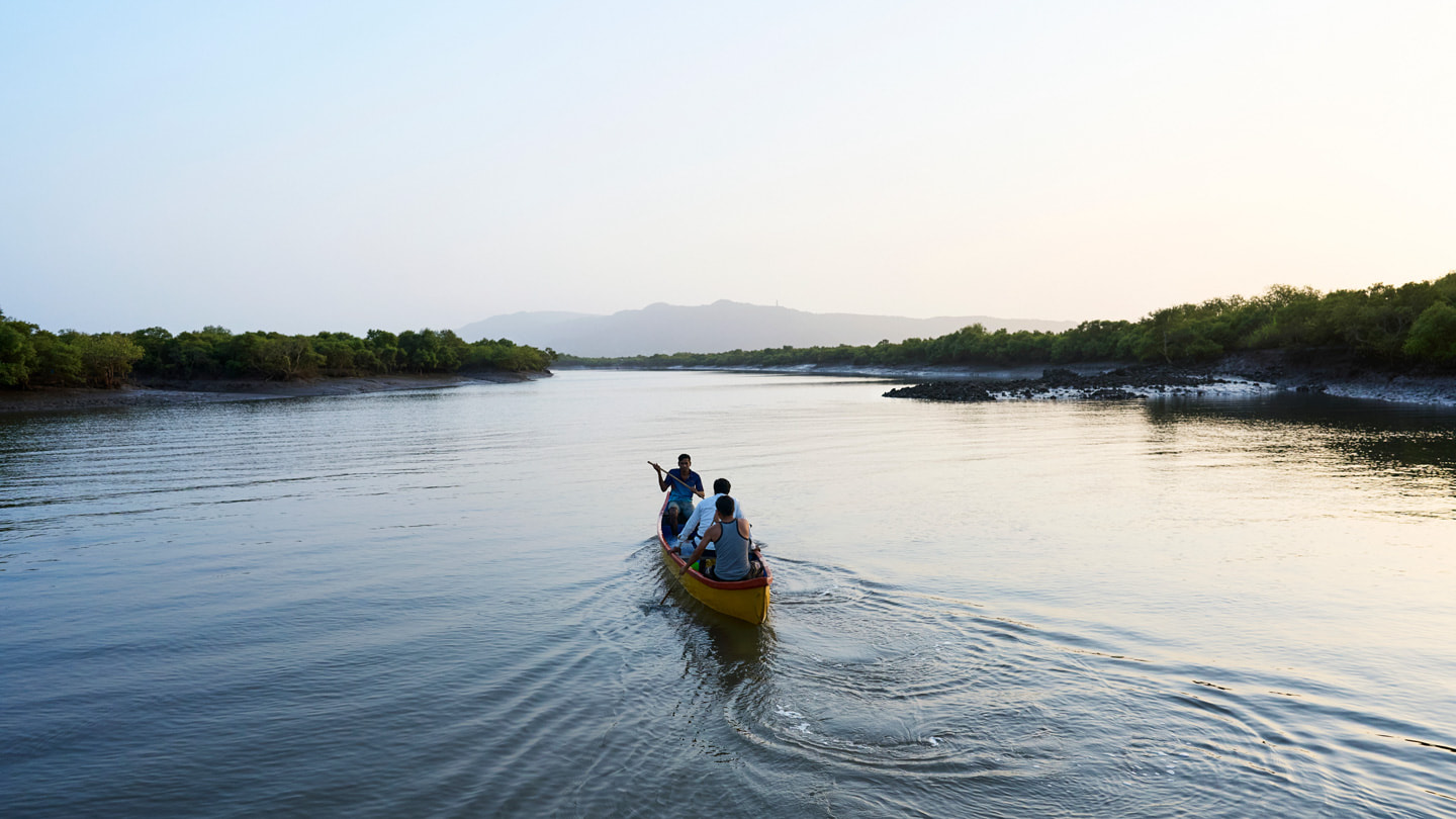 Tres personas en una canoa en un río de Maharashtra, India.