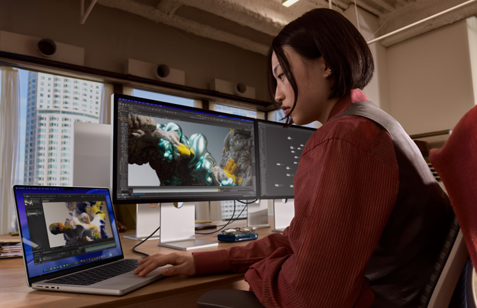 MacBook Pro’ya bağlı Studio Display XDR ile ofiste çalışan bir kişi