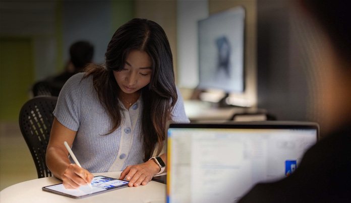 En universitetsstudent använder Apple Pencil för att anteckna på en iPad i ett tekniklabb