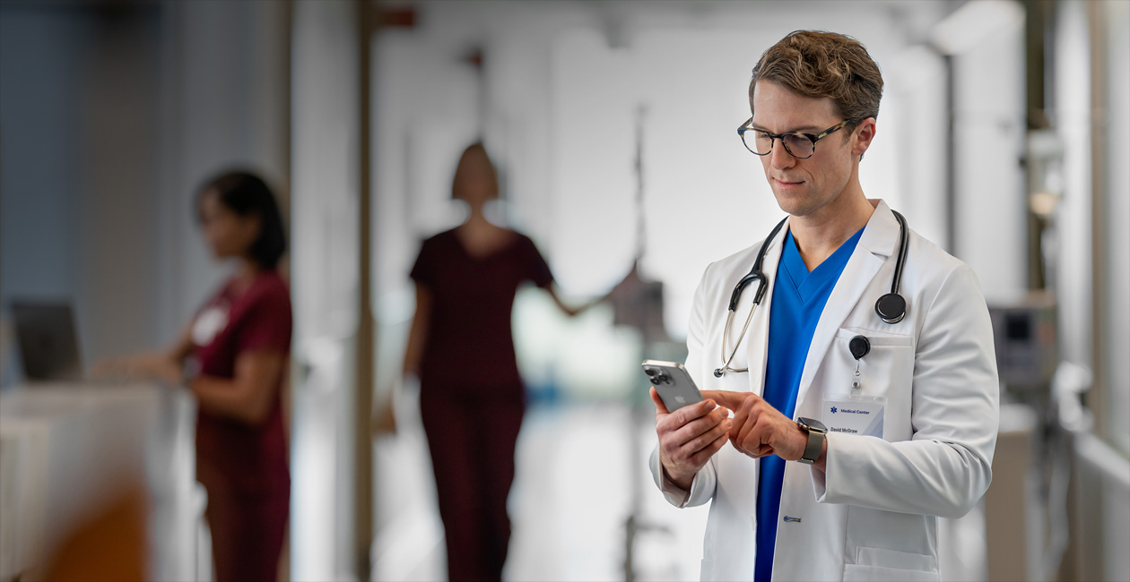 A male provider looking at his iPhone in a hospital.
