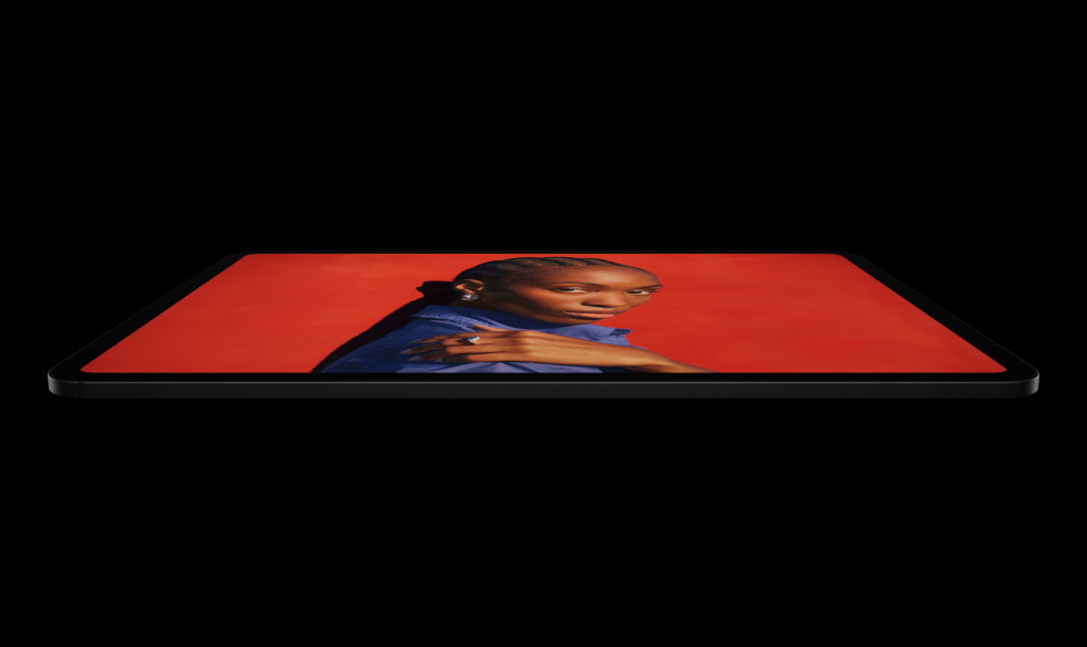 iPad Pro, side exterior, landscape orientation, space black colour, rounded corners, black display bezel, display showing an vibrant red screen with a individual posing with their hand on their shoulder wearing a blue shirt