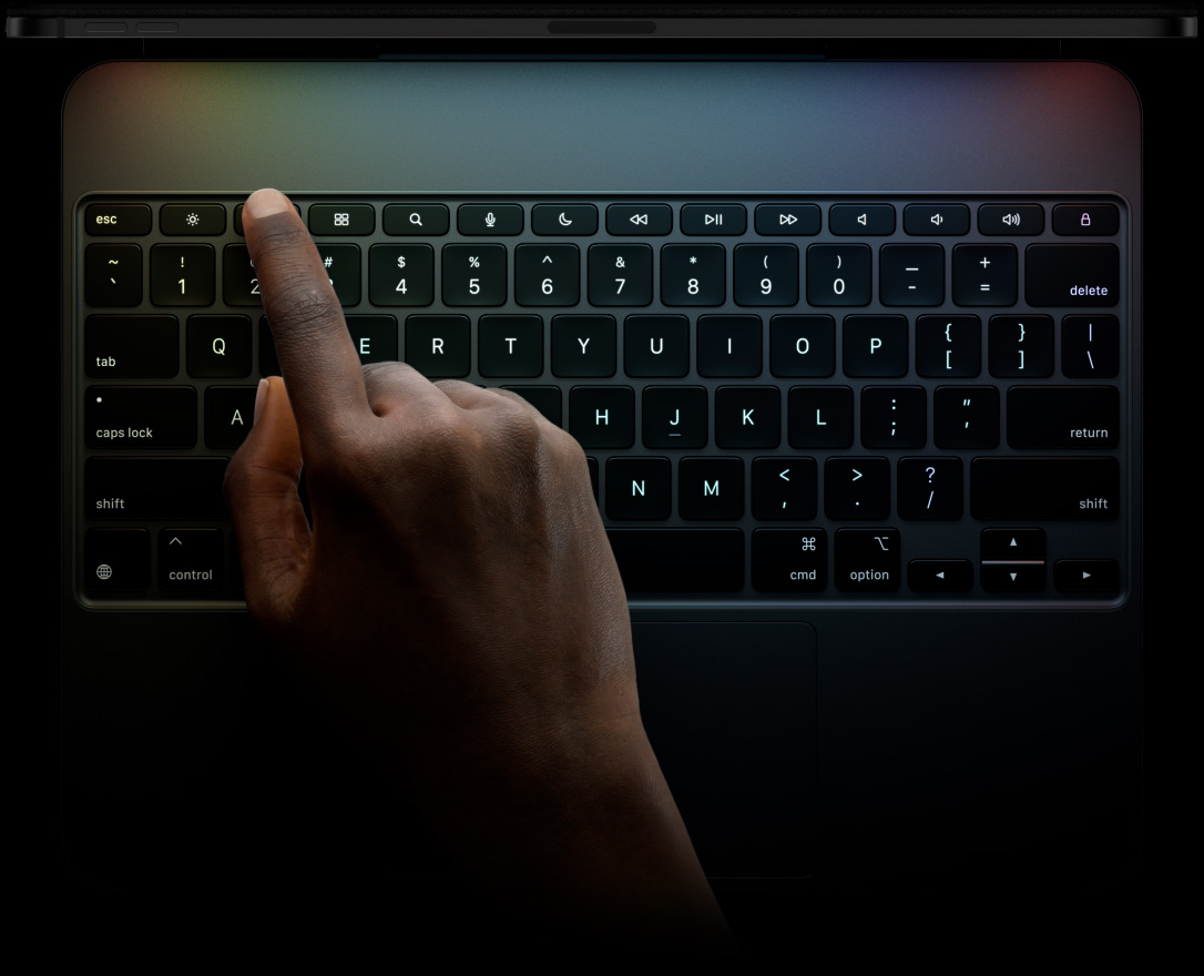 iPad Pro, landscape orientation, space black colour, top edge profile, attached to Magic Keyboard, front exterior, landscape orientation, black colour backlit keys, dedicated function key row, escape, tab, caps lock, shift, control, option, shift, delete, return, inverted-T arrow keys, built-in trackpad