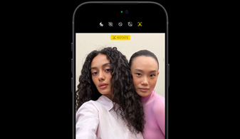 iPhone 18 Pro noir, de face, montrant deux personnes avec la fonctionnalité de suivi des visages, présentant la caméra avant Center Stage