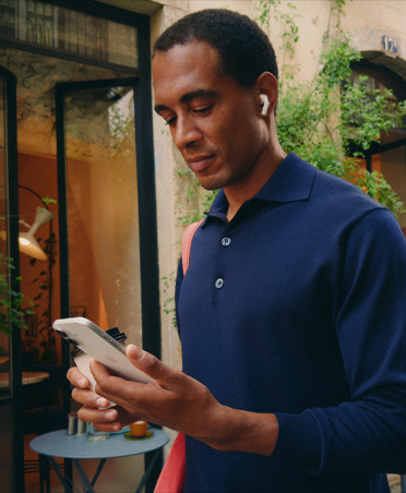 Seseorang di jalanan kota sedang melihat iPhone, mempertahankan koneksi Wi-Fi yang lancar di seluruh transfer jaringan